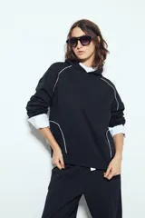 Canguro negro de silueta amplia con capucha integrada y detalles de líneas blancas que recorren el frente y las mangas.