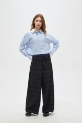 Pantalon de corte ancho y tiro alto, confeccionado en tela con estampado a cuadros en tonos verdes. Presenta cintura elástica con cordón de ajuste frontal.