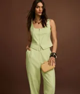 Pantalón zanahoria de vestir color verde claro, de tiro alto, con pliegues y bolsillos laterales.