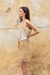 Pollera corta de diseño escalonado confeccionada en rafia con flecos largos que aportan movimiento. Presenta una estructura versátil que permite su uso también como top.