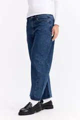 Jean de corte balloon con tiro alto y silueta amplia que se estrecha ligeramente hacia el tobillo. Presenta un diseño de cinco bolsillos, cierre frontal con botón y bragueta, y costuras reforzadas.