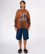 Buzo con capucha color marrón con efecto teñido/desgastado, estampado frontal grande con el número "76" con diseño de bandera estadounidense, un águila calva y una cinta con el texto "AMERICAN LOVE". Tiene bolsillo canguro y tres pines decorativos prendidos en la zona del hombro.