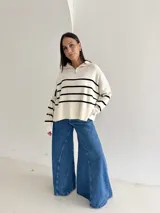 Sweater estilo chomba con cierre frontal, confeccionado en tejido bremer rayado de manga larga. Presenta un diseño amplio y moderno con cuello polo.