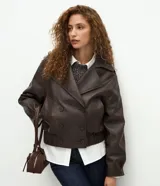Campera de cuero sintético color marrón oscuro, con diseño de cuello blazer, cierre frontal cruzado, mangas largas estructuradas y ruedo con elástico fruncido.