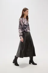 Falda midi de corte acampanado confeccionada en eco-cuero negro, con diseño de paneles y cintura alta.