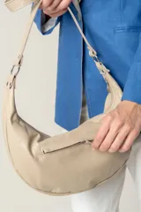 Cartera bandolera de cuero negro con diseño de media luna, decorada con tachas metálicas plateadas. Cuenta con correa regulable, cierre principal y bolsillo interior con forro.