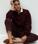 Pantalón modelo carrot de sarga, con cintura alta, pretina con presillas, cierre frontal con botón y cremallera, y bolsillos funcionales. Presenta un calce holgado en la cadera que se estrecha hacia el bajo.