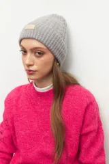 Gorro tipo beanie tejido en ochos, color gris, con detalle de etiqueta rectangular en el frente.