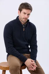 Buzo tejido de algodón en color azul marino, con cuello alto y cierre frontal parcial con tirador de cuero. Presenta puños y ruedo acanalados.