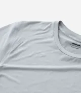 Remera deportiva de hombre con tecnología dry fit, cuello redondo y manga corta. Presenta un diseño liso en color beige con una pequeña etiqueta decorativa en el dobladillo.
