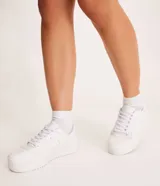 Championes blancos de caña baja con cordones, recortes laterales, puntera redonda y suela texturizada de 4cm de altura.