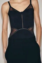 Body de escote corazón con aros y tirantes finos ajustables. Presenta un diseño con paneles de tejido opaco y transparencias laterales. Cierre inferior con botones a presión.