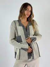 Saco de punto color naranja con detalles de rayas horizontales en las mangas y franjas verticales en el cuerpo. Tiene cuello tipo polo, cierre frontal con botones y un bolsillo decorativo en el pecho.