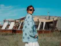 Campera de denim con estampado de lunares grandes en tono azul oscuro sobre fondo celeste. Presenta corte oversize, cierre frontal con botones metálicos y bolsillos frontales con solapa.