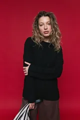 Sweater de tejido de punto negro con tramas de ochos en las mangas y laterales, cuello redondo a la base y mangas largas.