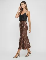 Falda midi de satén con estampado animal print en tonos marrones y negros. Corte al bies que cae ajustado en la cadera y se abre ligeramente hacia el ruedo.