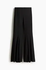 Pantalón negro de punto suave, tiro alto con cintura elástica oculta y corte extraajustado con costuras decorativas. Presenta nesgas en las rodillas que generan un diseño acampanado y fluido en los bajos.