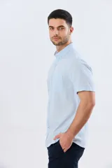 Camisa de manga corta confeccionada en mezcla de lino y algodón, color beige, con cuello camisero abotonado, bolsillo frontal en el pecho y cierre de botones.