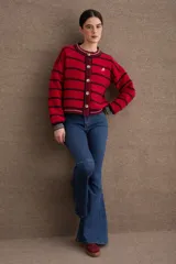 Cardigan de punto con diseño a rayas horizontales en azul marino y beige. Presenta cuello redondo, cierre frontal con botones grandes y mangas largas con puños acanalados en tono verde oliva. Incluye un pequeño bordado de una raqueta de tenis en el lateral.