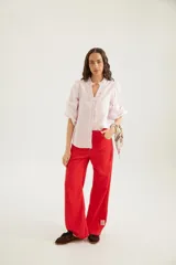 Pantalón de corte recto y tiro medio con costuras a la vista, bolsillos delanteros y traseros, y un detalle de pin de la marca en el ruedo.