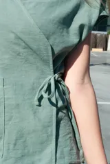 Blusa color beige con cuello camisero, corte cruzado, mangas cortas y lazo lateral.