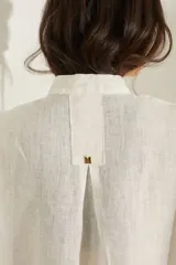 Vestido corto color beige de lino, con moldería amplia, manga corta, cuello mao y cierre frontal con botones dorados.