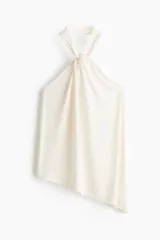 Top halter color marfil con bajo asimétrico y detalle drapeado en la parte superior.