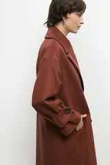 Abrigo de paño de lana con cuello alto estructurado, cierre frontal y mangas largas con detalle de botón en el puño.