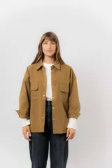 Sobrecamisa de gabardina liviana color crema, con corte oversize, cuello clásico, cierre frontal con botones a presión y dos bolsillos delanteros con solapa.