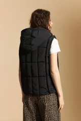 Chaleco acolchado de nylon color negro, con diseño capitoneado, capucha integrada y cierre frontal con tirador metálico.