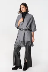 Ruana de tejido suave y envolvente en color blanco, con diseño de corte amplio y terminación de flecos en el ruedo.