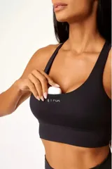 Top deportivo de alto rendimiento con diseño de espalda nadador, confeccionado en tejido técnico con protección UV50+. Presenta un corte ajustado, banda elástica inferior para mayor soporte y bolsillos integrados para objetos pequeños.