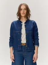 Campera de denim azul con cuello mao, cierre frontal con botones metálicos y presillas decorativas.