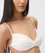 Top de bikini blanco con diseño de media taza, breteles finos y detalle de aplique frontal con forma de concha.