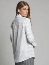 Camisa azul con rayas verticales blancas, de corte clásico, con cuello camisero y mangas largas.