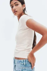 Top ajustado de manga corta con escote amplio que deja los hombros descubiertos, ribeteado con encaje blanco. El tejido es de punto de algodón con rayas finas verticales en tonos rosado pálido y blanco.