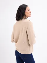 Campera de tejido de punto en color beige, con cierre frontal completo, cuello alto y mangas largas con puños acanalados.