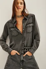 Camisa de estilo tejano en denim gris con efecto lavado, cuello camisero, cierre frontal con botones metálicos y dos bolsillos delanteros con solapa.