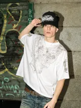 Remera de algodón pesado con corte boxy fit, color blanco con efecto acid wash. Presenta un estampado frontal y en mangas que simula una armadura medieval con acabado gastado.