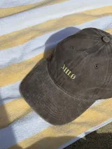 Gorra tipo dad hat color bordó con efecto lavado, con el logo de la marca bordado en hilo color crema en la parte frontal.