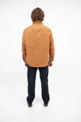 Camisa de pana color camel, de corte recto, con cuello abotonado y bolsillo en el pecho.