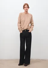 Jersey de punto trenzado color beige, con cuello redondo, manga larga y detalles de calados en el frente y las mangas.