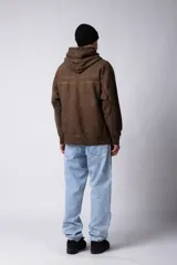 Buzo canguro de frisa gruesa con capucha, diseño oversize y acabado con efecto gastado. Presenta recortes horizontales en el frente y puños con elástico.