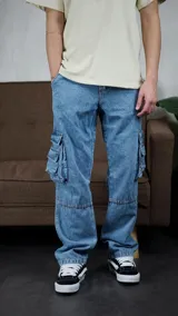 Pantalón cargo de denim en color azul lavado, con corte holgado y costuras reforzadas en las rodillas. Presenta bolsillos laterales tipo cargo con solapa y cierre de botones.