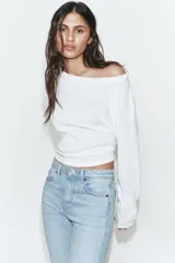 Jeans de tiro alto con diseño cropped flare, confeccionados en denim azul con acabado desgastado. Presentan cinco bolsillos, cierre frontal con cremallera y botón metálico, y bajo con terminación sin costuras.