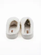 Pantuflas de peluche color blanco con diseño de corazón en relieve en la parte superior y suela de plataforma acolchada.
