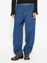 Pantalón de jean azul, corte slouch tipo babucha, con cintura elástica a contratono, bolsillos plaqué y recortes.