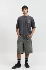 Remera gris oscuro con efecto gastado, corte boxy, manga corta y cuello redondo. Estampado en el frente con diseño abstracto y texto 'mistral'.