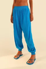 Pantalón babucha azul con brillos de látex, cinturilla ancha de látex, diseño amplio en crepé de viscosa con detalle de hilos de colores verticales a lo largo del pantalón y diseño recto con solapa elástica rematando el bajo.