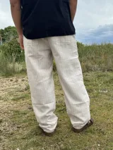 Pantalón de lino beige y crudo a rayas, de corte ancho y relajado.